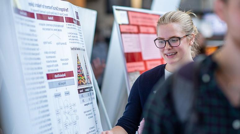 A student looks at a presentational poster at the Steinmetz Symposium